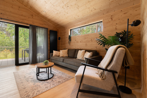 Moderne opholdsstue i træ på Terrace Chalet, Bospark Markelo, med store vinduer og grønt udsyn.
