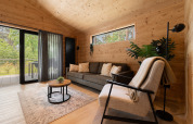 Modern wooden living room at Terrace Chalet, Bospark Markelo, Netherlands, featuring forest views outside.