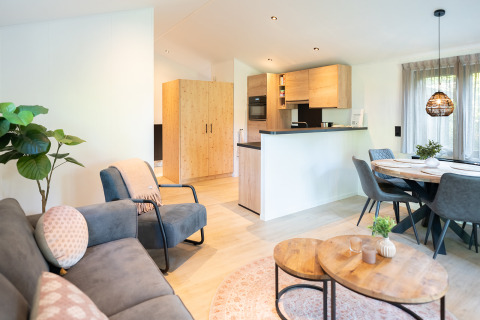 Modernes Wohnzimmer und Küche in einer Terrasse Chalet im Bospark Markelo, Niederlande, mit Holzmöbeln.