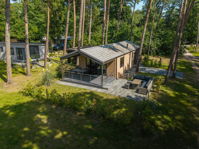 Chalet con terraza en Bospark Markelo, Países Bajos, rodeado de bosque y zona de estar exterior moderna.