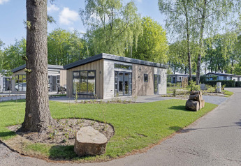 Lodge Nova 4 personnes moderne et lumineux, entouré d’arbres et gazon dans une atmosphère tranquille.