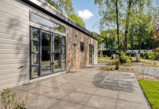 Moderne lodge Nova 4 personen in Bospark Ede, Nederland, met terras en zicht op bomen en natuur.