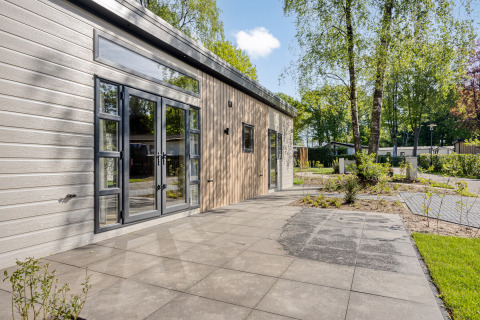 Lodge moderne Nova 4 personnes à Bospark Ede, Pays-Bas, terrasse et vue sur des arbres en environnement paisible.