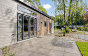 Lodge moderne Nova 4 personnes à Bospark Ede, Pays-Bas, terrasse et vue sur des arbres en environnement paisible.