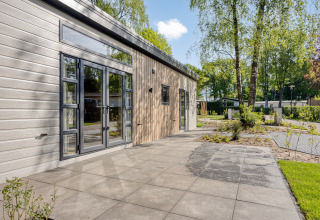 Lodge moderne Nova 4 personnes à Bospark Ede, Pays-Bas, terrasse et vue sur des arbres en environnement paisible.