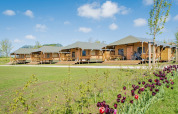 Safari tents at Camping Waddenzee holiday park in North Holland, Netherlands, with flowers and bikes nearby.