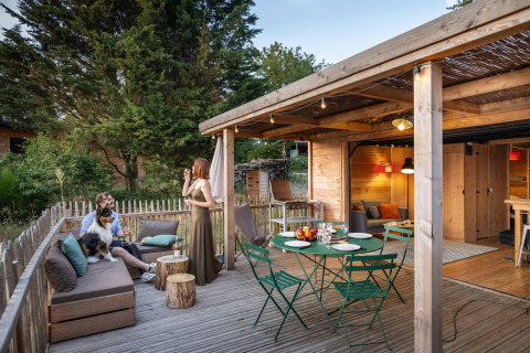 Alojamiento glamping en Village Huttopia Pays de Condrieu, terraza exterior y cabaña de madera en el bosque.