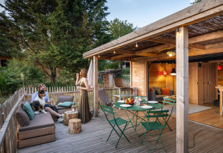 Alojamiento glamping en Village Huttopia Pays de Condrieu, terraza exterior y cabaña de madera en el bosque.