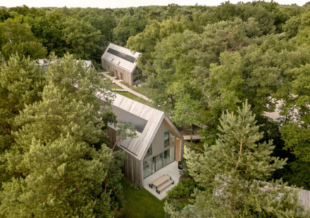 Luchtfoto van Group Lodge met moderne houten huisjes, omringd door dicht bos en wandelpaden.