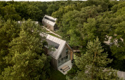 Luchtfoto van Group Lodge met moderne houten cabines, ingebed midden in het groene, bosrijke landschap.