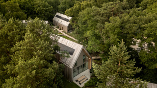 Vista aérea de Group Lodge con cabañas de madera modernas rodeadas de bosque denso y senderos naturales.