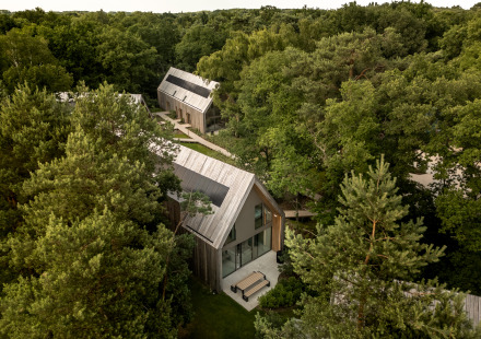 Luchtfoto van Group Lodge met moderne houten huisjes, omringd door dicht bos en wandelpaden.