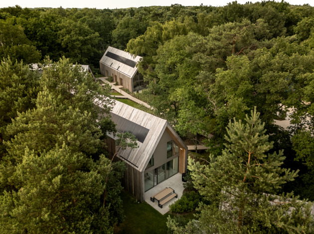Luchtfoto van Group Lodge met moderne houten huisjes, omringd door dicht bos en wandelpaden.