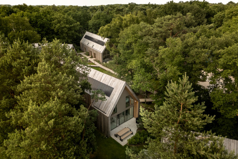 Vista aérea de Group Lodge con cabañas de madera modernas rodeadas de bosque denso y senderos naturales.