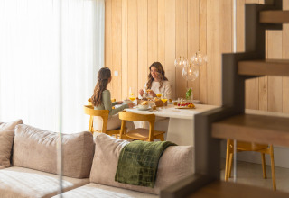Deux femmes savourent un petit déjeuner à une table en bois dans un lodge moderne et chaleureux.