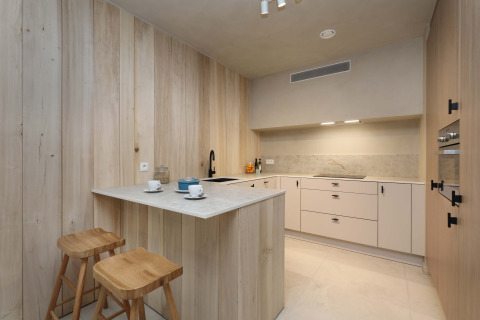 Cocina moderna con paneles de madera clara y taburetes en Group Lodge de Woodz Lodges en Bélgica.