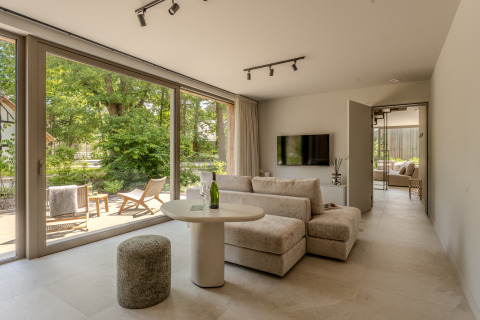 Modernes Wohnzimmer in der Group Lodge bei Woodz Lodges in Belgien mit Blick auf Terrasse und Natur.