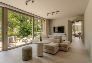 Salón moderno en Group Lodge de Woodz Lodges, Bélgica, con grandes ventanales y vista a la terraza.