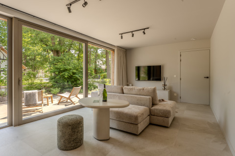 Espacioso salón en Group Lodge en Woodz Lodges, Bélgica, con grandes ventanales y vistas a la naturaleza.