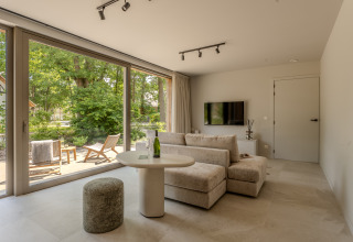 Espacioso salón en Group Lodge en Woodz Lodges, Bélgica, con grandes ventanales y vistas a la naturaleza.