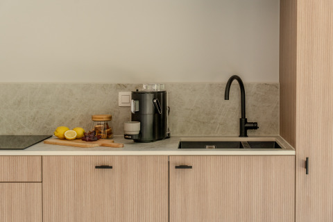 Cocina moderna en Group Lodge, Woodz Lodges, Bélgica, con grifo negro, frutas y cafetera.