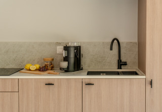 Cocina moderna en Group Lodge, Woodz Lodges, Bélgica, con grifo negro, frutas y cafetera.