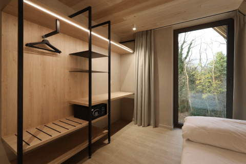 Dressing moderne en bois avec étagères et coffre-fort face à une fenêtre, Group Lodge, Woodz Lodges, Belgique.