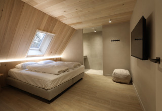 Modernes Schlafzimmer in der Group Lodge bei Woodz Lodges in Belgien mit Holzdecke und Dachfenster.