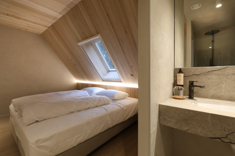 Chambre moderne et salle de bains à Group Lodge chez Woodz Lodges en Belgique, avec bois et lumière.