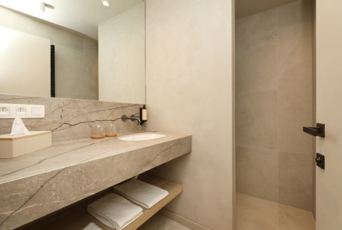 Baño moderno en Group Lodge de Woodz Lodges, Bélgica, con lavabo de mármol, espejo grande y toallas blancas.