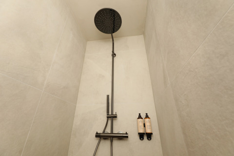Ducha moderna con cabezal tipo lluvia y dos botellas montadas en la pared en Group Lodge de Woodz Lodges, Bélgica.
