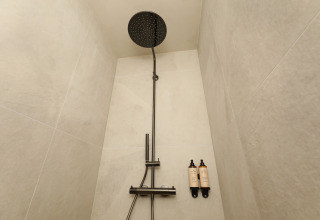 Ducha moderna con cabezal tipo lluvia y dos botellas montadas en la pared en Group Lodge de Woodz Lodges, Bélgica.