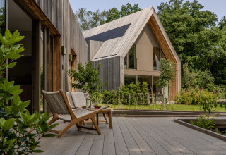Lodge moderno de madera con terraza y grandes ventanas, rodeado de naturaleza en Woodz Lodges, Bélgica.