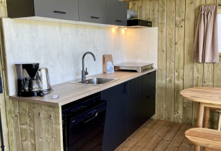 Modern kitchenette in the Luna Lodge safari tent at Camping the Noetselerberg in the Netherlands with wood decor.