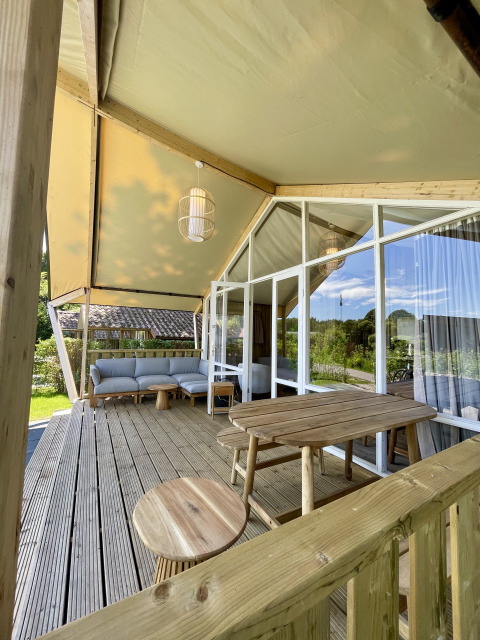 Wooden deck with rustic furniture at Luna Lodge safari tent, Camping the Noetselerberg, Netherlands.