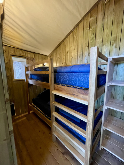 Vista interior de la tienda safari Luna Lodge con literas y paredes de madera en Camping the Noetselerberg, Países Bajos.
