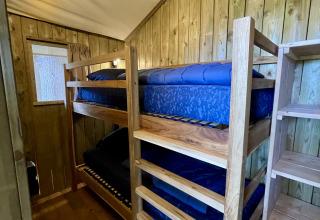 Vista interior de la tienda safari Luna Lodge con literas y paredes de madera en Camping the Noetselerberg, Países Bajos.