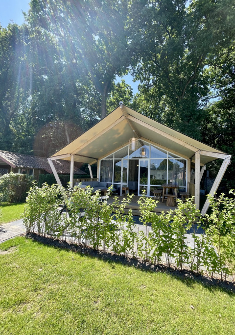 Safari tent Luna Lodge at Camping the Noetselerberg in the Netherlands, surrounded by greenery and sunlight.