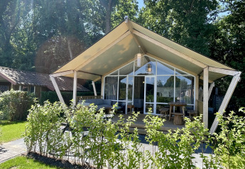 Tenda safari Luna Lodge presso Camping the Noetselerberg nei Paesi Bassi, circondata dal verde e dal sole.