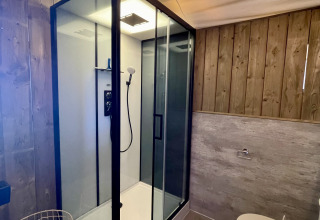 Baño moderno en la tienda safari Luna Lodge de Camping de Noetselerberg con ducha acristalada y madera.