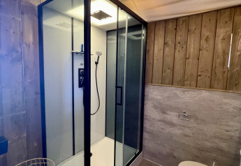 Baño moderno en la tienda safari Luna Lodge de Camping de Noetselerberg con ducha acristalada y madera.