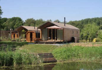 Wrap house lodge with sauna and bathtub at Resort de Parel, set in lush greenery in the Netherlands.