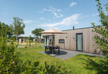Moderne Holz-Lodge mit Terrasse, Sitzbereich und Sonnenschirm im Vakantiepark Hölte in den Niederlanden.