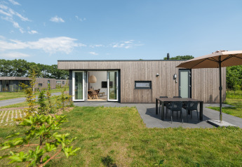 Moderne Holzhütte mit Terrasse, Esstisch und Sonnenschirm im Vakantiepark Hölte in den Niederlanden.