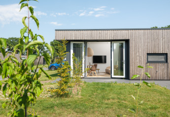 Moderne træhytte kaldet Oak lodge ved Vakantiepark Hölte i Nederlandene med åbne døre og grøn have.