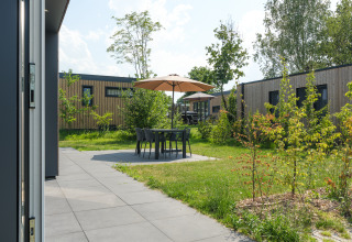 Außenterrasse am Oak Lodge im Vakantiepark Hölte, Niederlande, mit Tisch, Stühlen und Sonnenschirm.