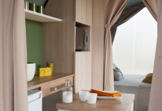 Binnenzicht van een Coco Sweet safaritent bij Camping Seasonova Haliotis in Frankrijk met keuken en bed.