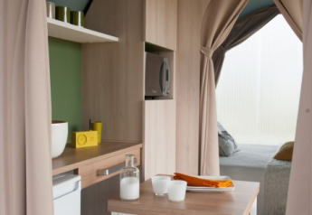 Interior view of a Coco Sweet safari tent at Camping Seasonova Haliotis, France, showing kitchen and bed area.