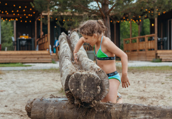Fille en bikini vert grimpant sur des troncs à Tiny Wander Lodge au Holiday Park Sallandshoeve, Pays-Bas.