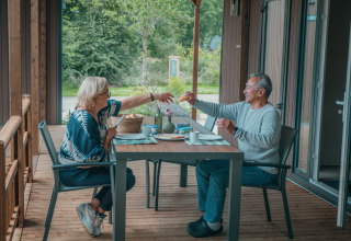 Zwei Personen frühstücken auf der Terrasse der Tiny Wander Lodge im Holiday Park Sallandshoeve, Niederlande.